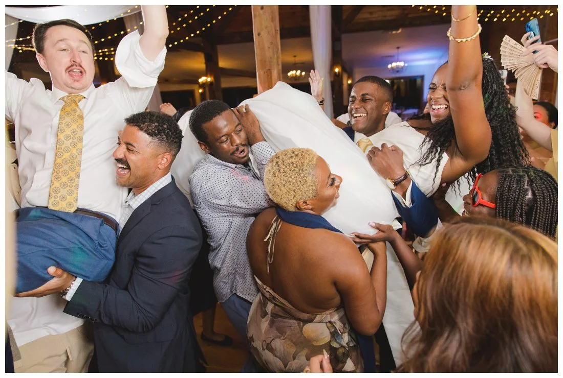 guests lift bride and groom on the dance floor