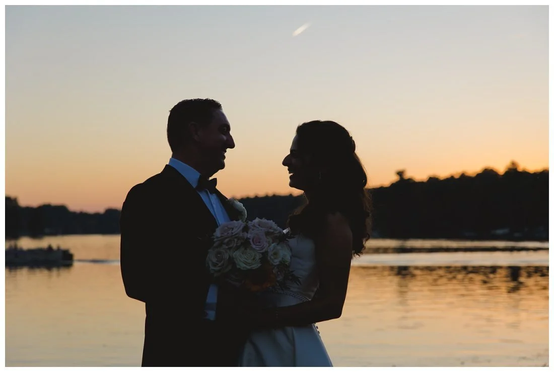 silhouette sunset photo of bride and groom in front of lake