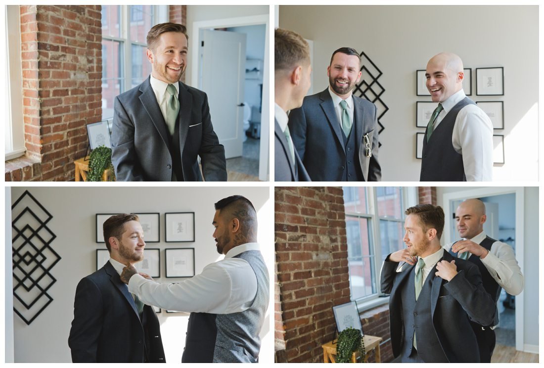 groom gets ready in suite with industrial vibe bricks, groomsmen help him get his coat and tie on