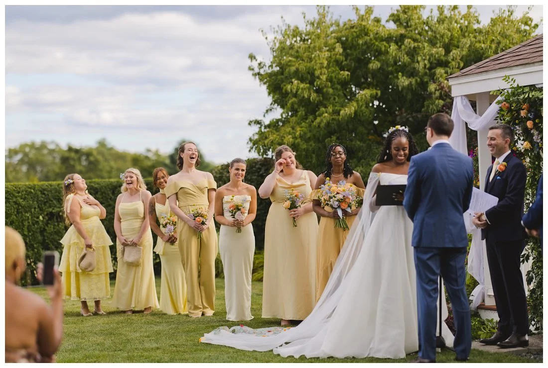 bridesmaids laugh and wipe their eyes while bride reads her vows