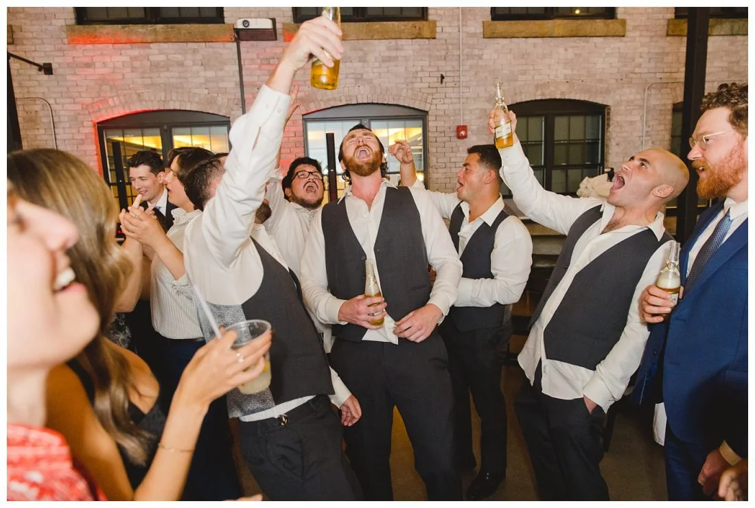 groomsmen sing and raise their beers on the dance floor