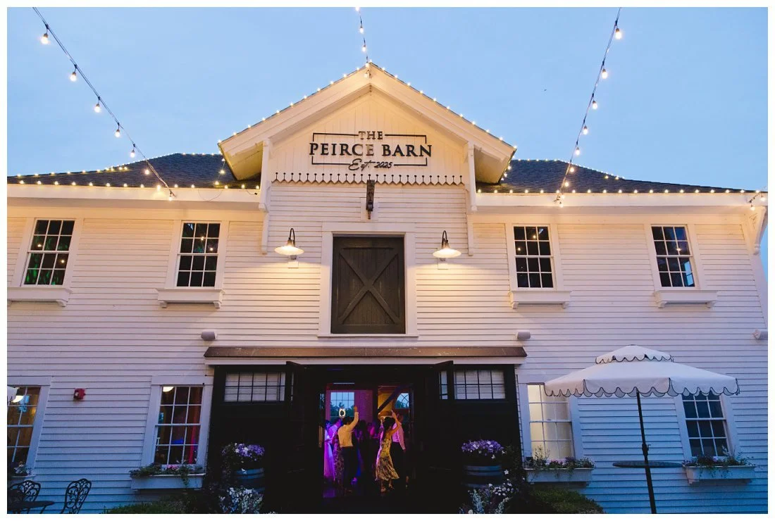the peirce barn at sunset with the cafe lights lit up and dance floor lights coming through the front doors