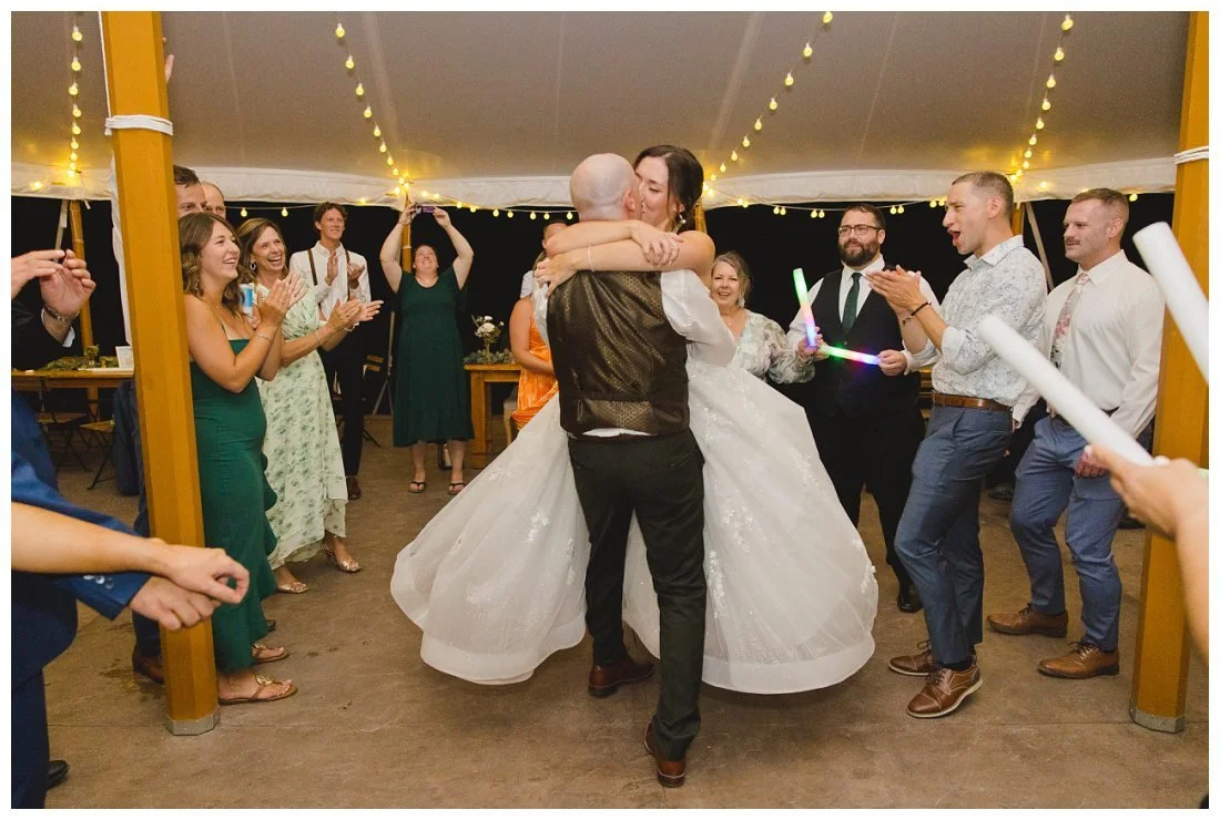 groom picks up bride and swings her around while kissing at last dance