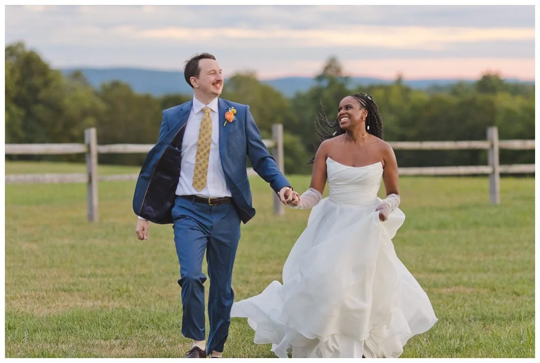 bride and groom run through field at sunset
