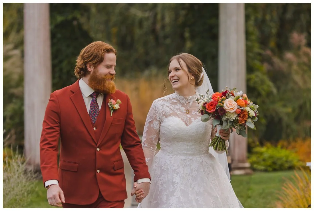 wedding photos laughing bride and groom walking and holding hands looking at each other