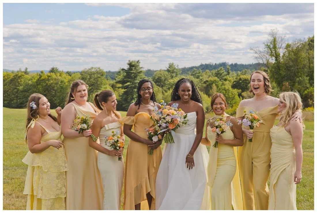 bride laughs with her bridesmaids, who wear various colors of yellow