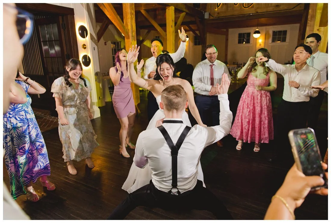 bride and groom dance in the middle of a circle of their family and friends at barn reception