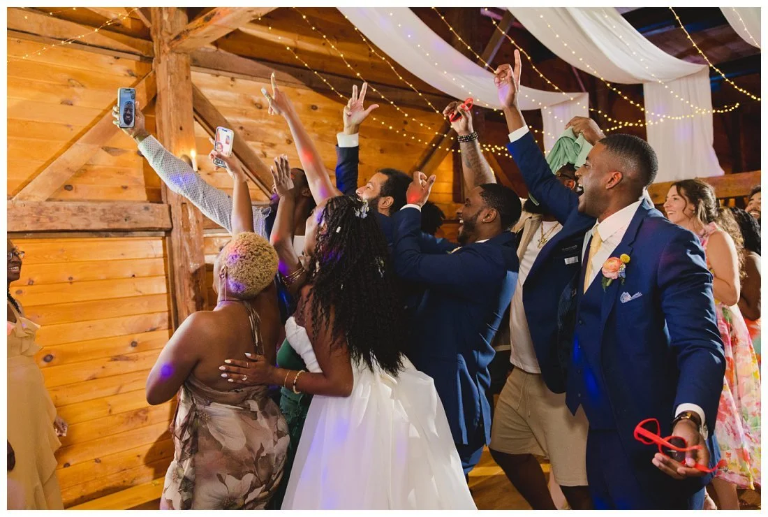 everyone cheers as a guest holds up a phone facetiming with relative at wedding reception