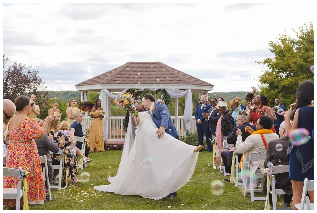 groom dips bride in the middle of the wedding ceremony aisle