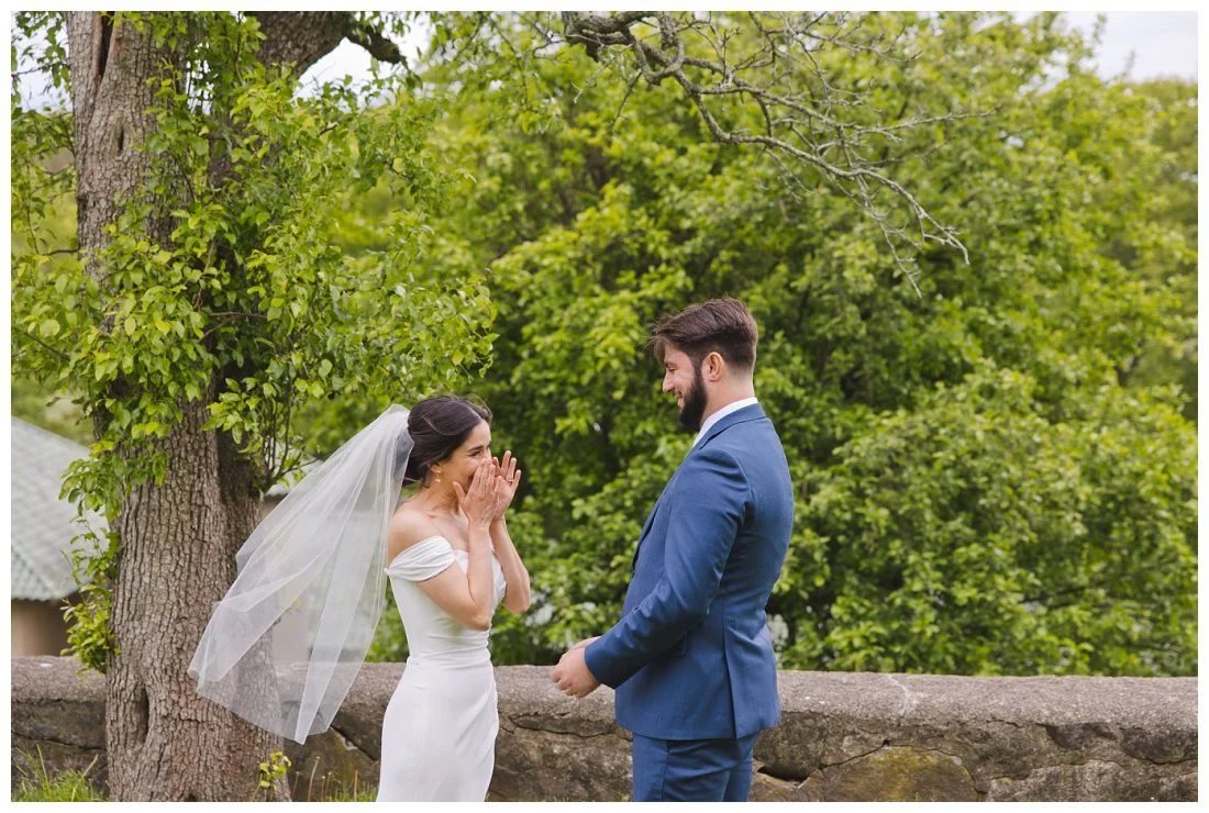 bride holds her hands to her face during emotional moment during first look wedding