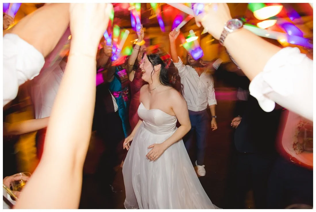 fun dancing photo of bride with light up glow sticks all around her with lots of colors