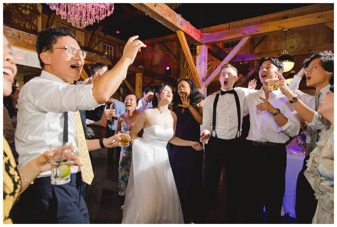 wedding couple and guests sing along to a song on the dance floor