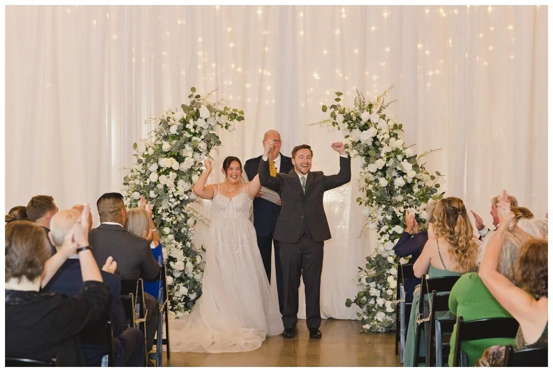 nick and natalie put their arms up and cheer at the end of their wedding ceremony