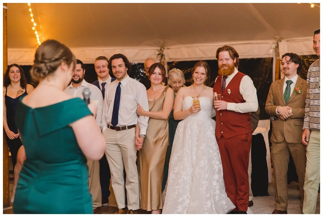 maid of honor gives toast and guests and couple smile and laugh