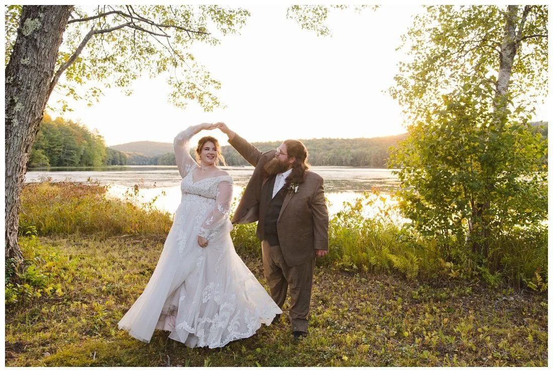 groom twirls bride and her dress flares out during golden hour photos at the lake with nh mountain in the background