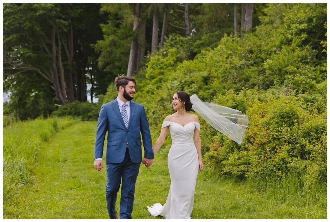 jon and mira walk along green path from the woodlands at barn at crane estate