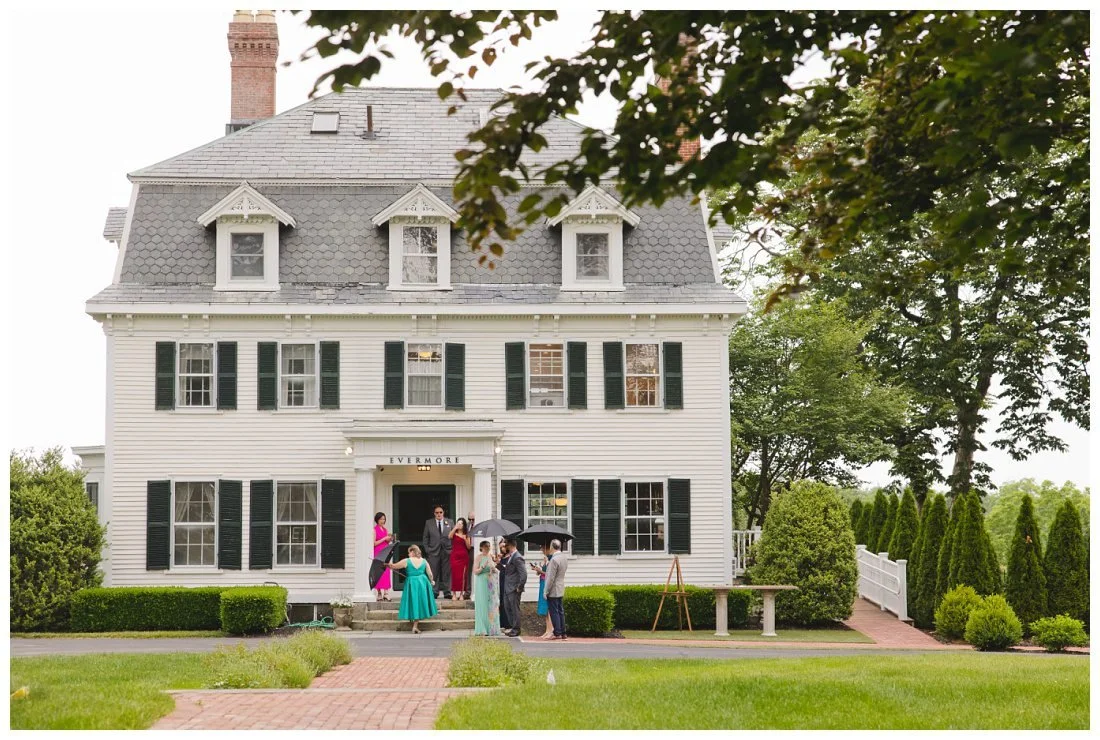 guests outside of the estate house holding umbrellas at the evermore at peirce farm
