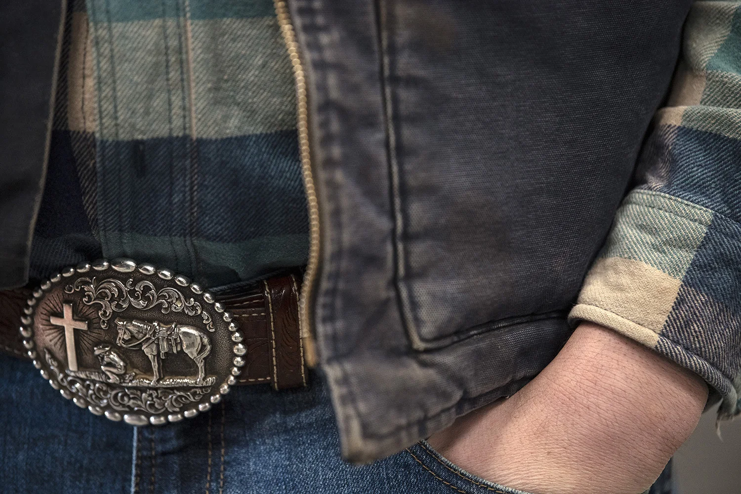  Josiah Williams tucks his hand in his pocket as he talks to Kalmbach Feeds representative Levi Richards, of Bowling Green, Ohio, about the quality of their hay and feed. Williams wears a belt buckle that embodies the way of life for many in this par