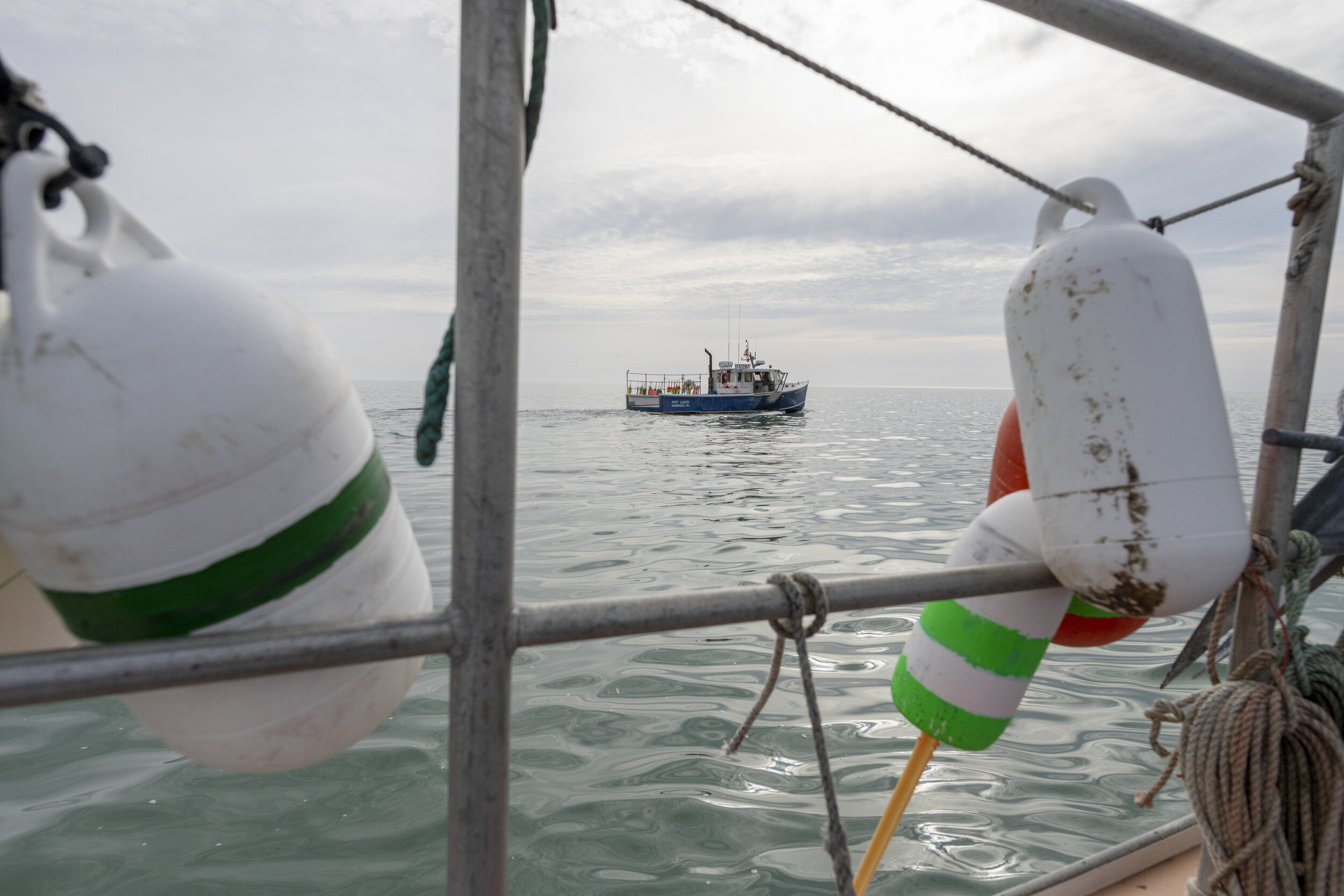 The lobster boat, Pot Luck, is seen from the deck of its sister boat, the Kestrel, on a chilly January morning in Cape Cod Bay. Peter Mason’s father owns and operates the Pot Luck, but since injuring his hip, his grandson, Toby Mason, has taken over