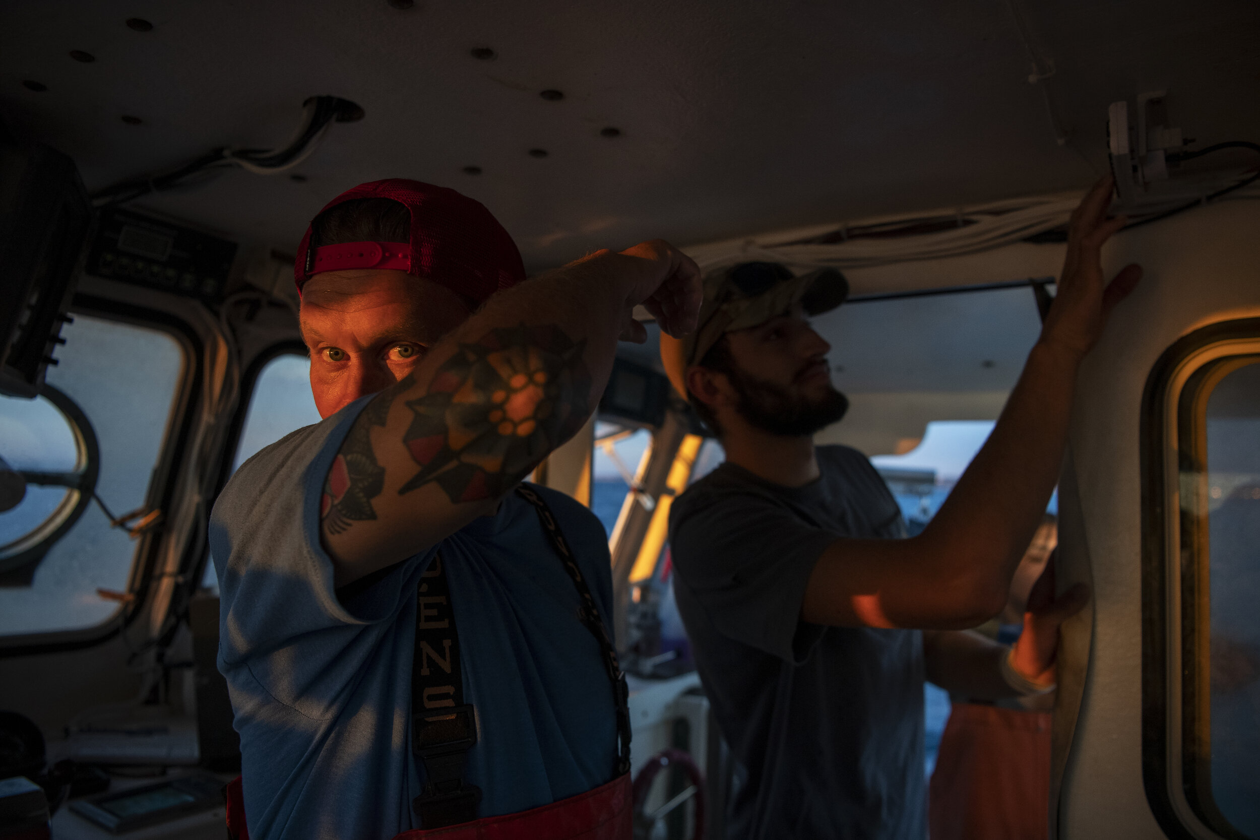 Lobsterman Peter Mason and his son, Toby Mason, tune their radio to find music to listen to as they begin to set and haul lobster pots on their lobster boat, Pot Luck, while the sun starts to rise above the horizon.
