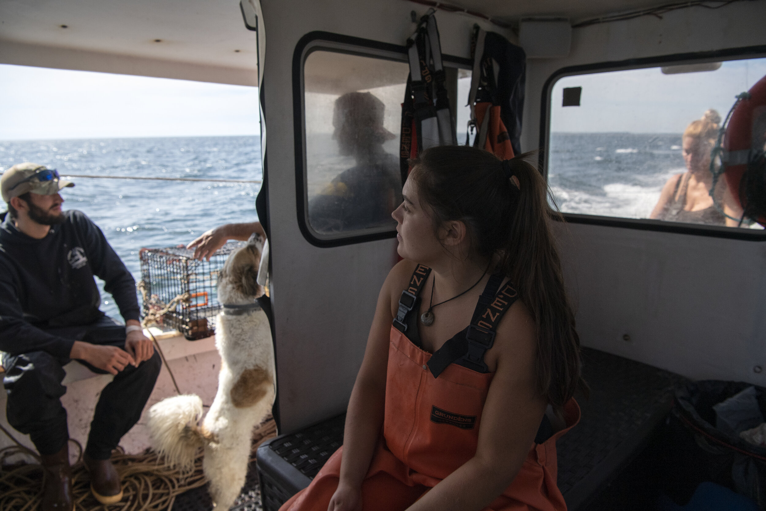 From left, Toby Mason, his dog, Huey, father, Peter Mason, girlfriend, Caroline Howlett, and sternman Cara Delaney, rest and prep before setting a new line of lobster traps in Cape Cod Bay.