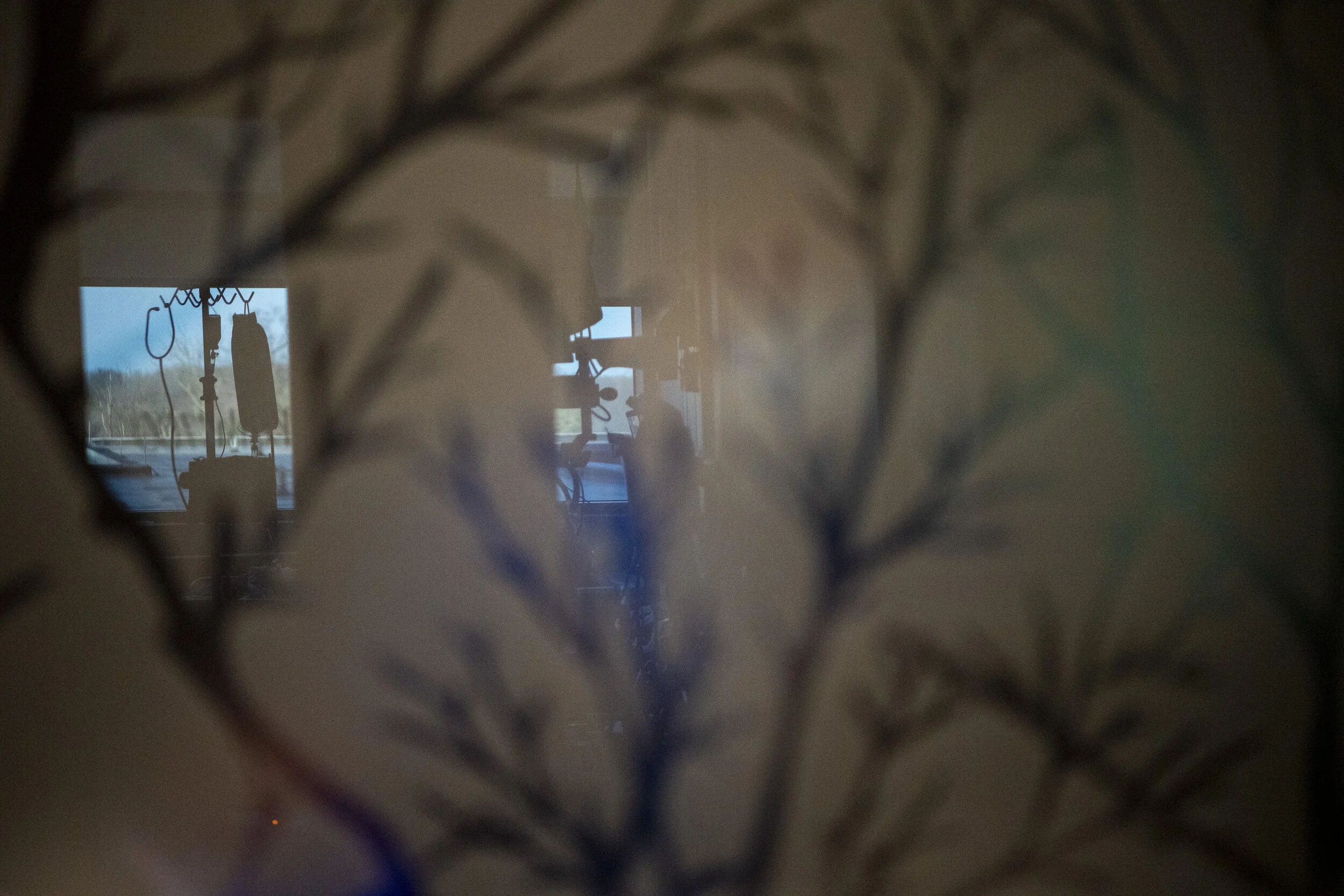  A patient’s room is reflected in glass along the hallway of the ward. 