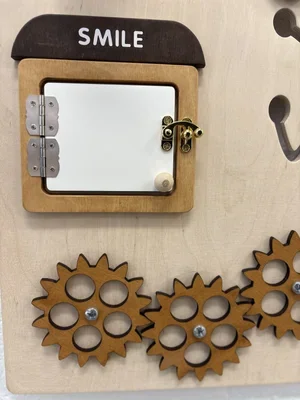 Decorative wooden wall art with a small mirror, gears, and a sign that says 'SMILE' at the top.