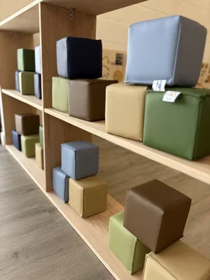 Colorful cubic-shaped cushions displayed on wooden shelves in a store.