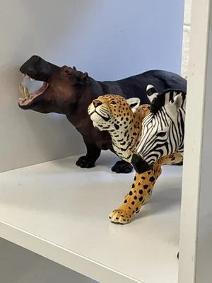 Collection of animal figures including a black panther, a cheetah, and a zebra, displayed on a white surface.