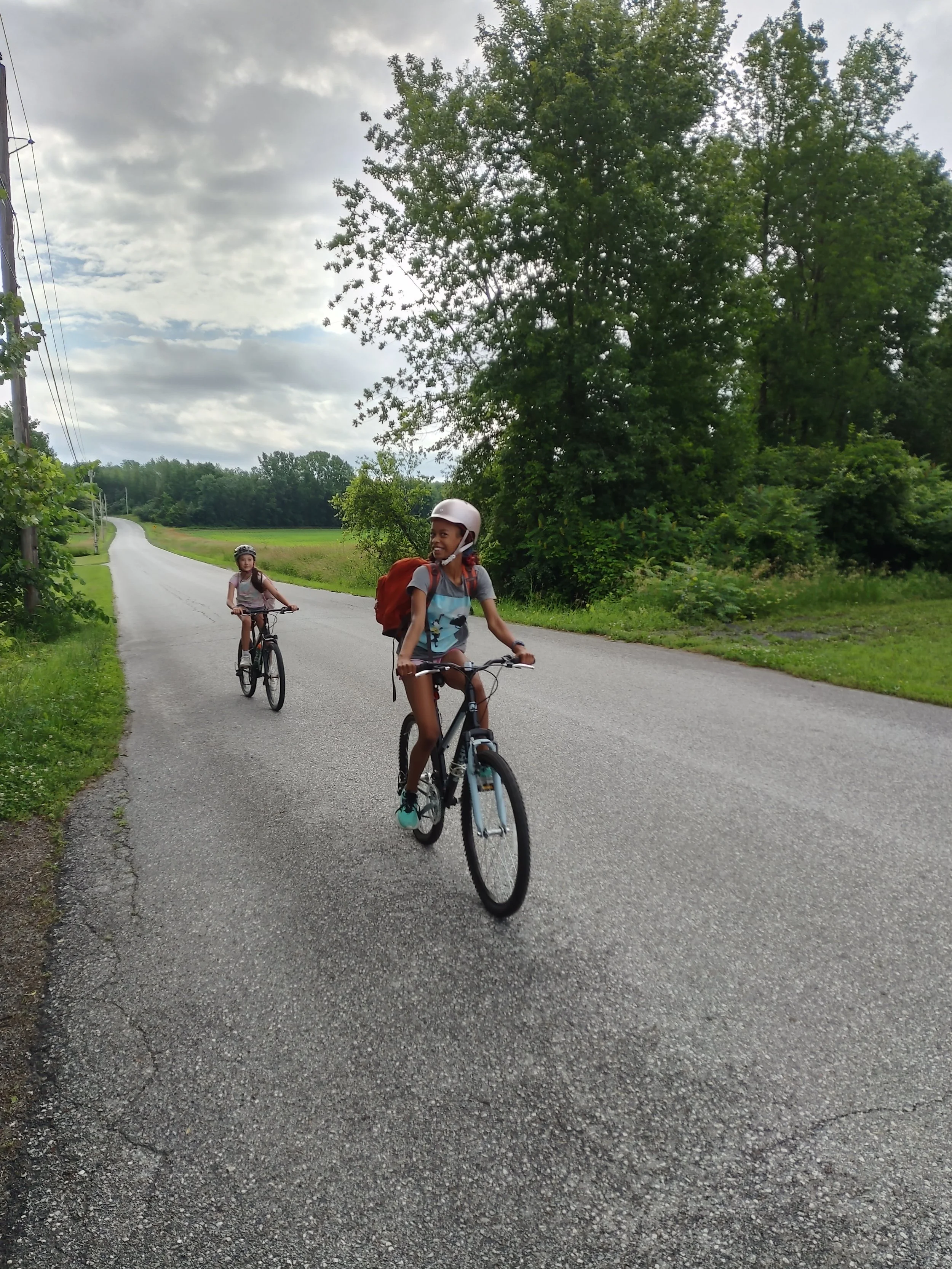 two campers riding their bikes toward the camera and smiling