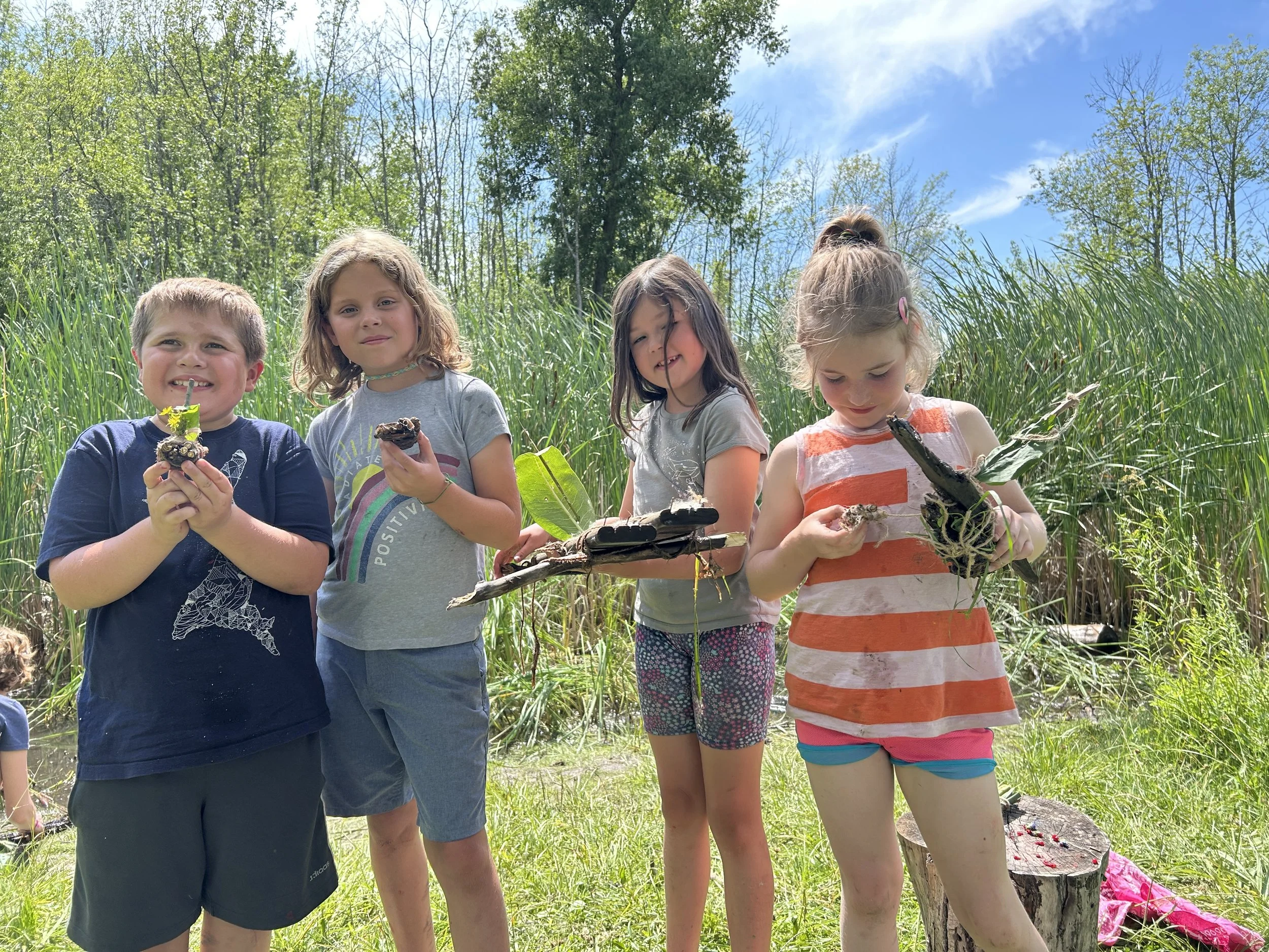 4 summer campers at the Rec Park, holding small hand-made rafts