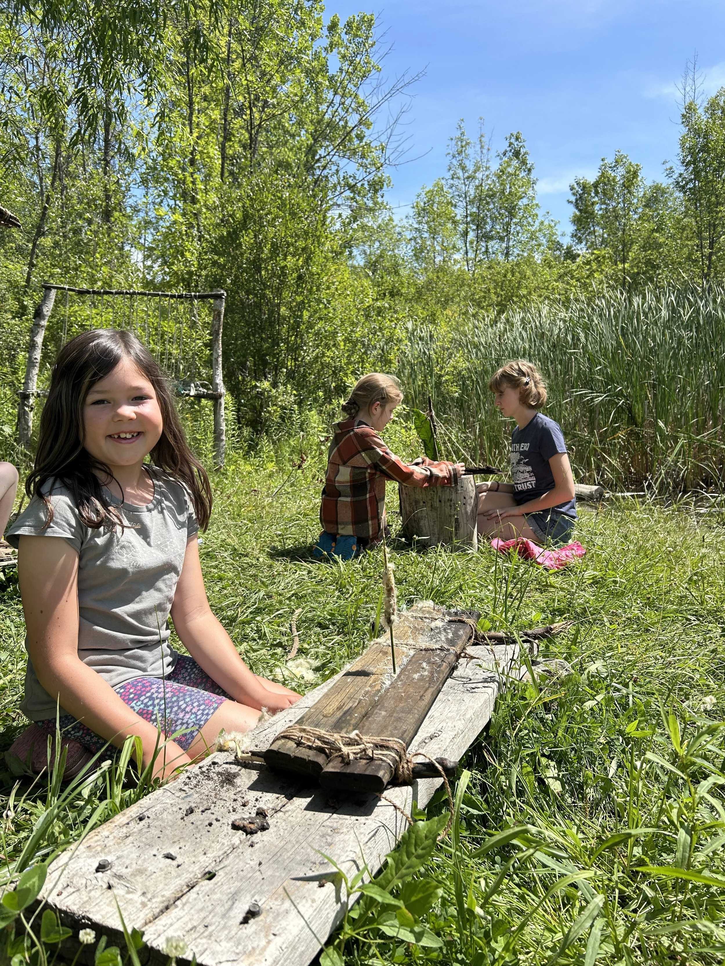 a camper showing off her "fairy raft", while another camper and SHLT volunteer work on theirs in the background