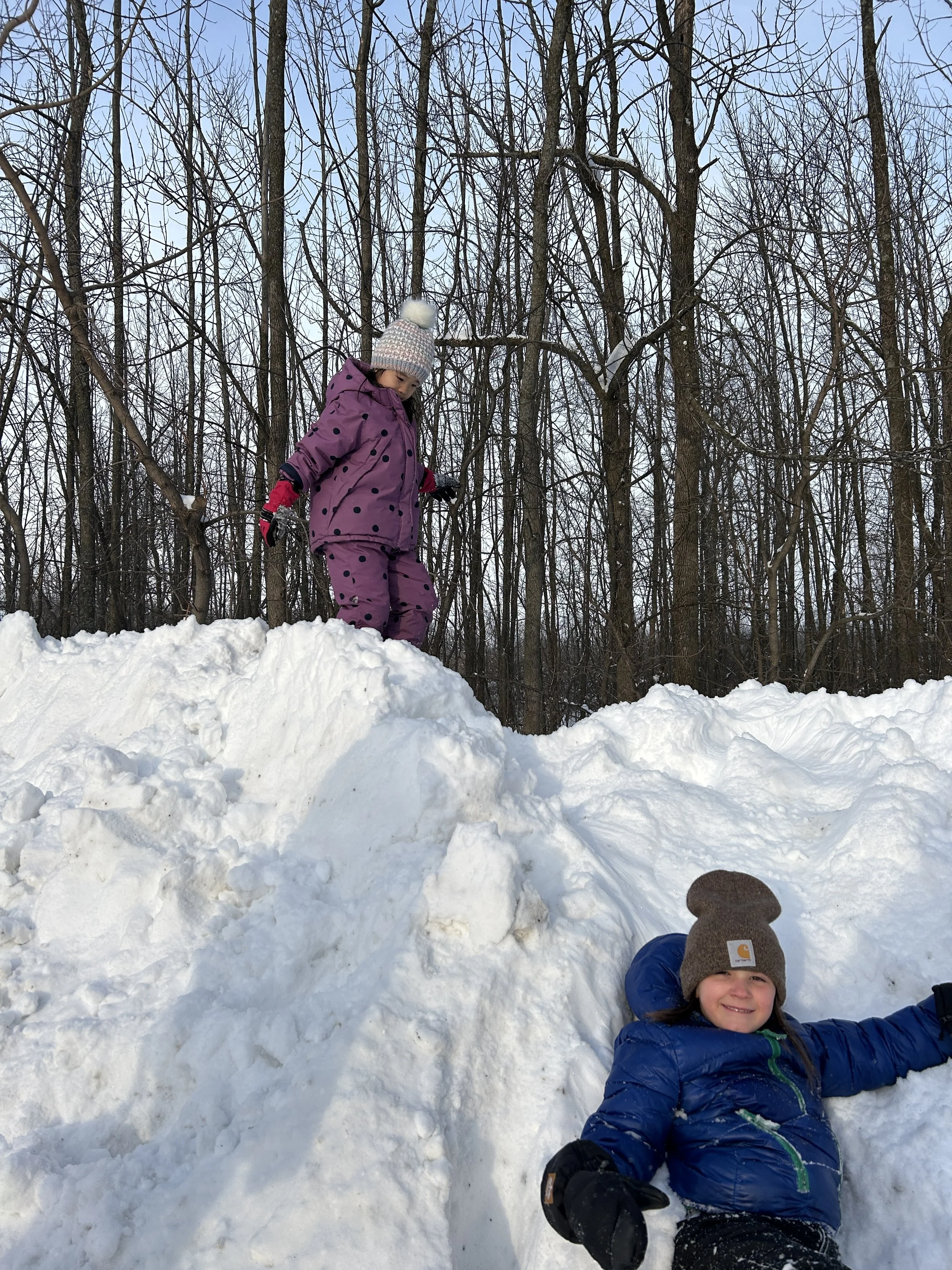 two young children climbing a large snowbank