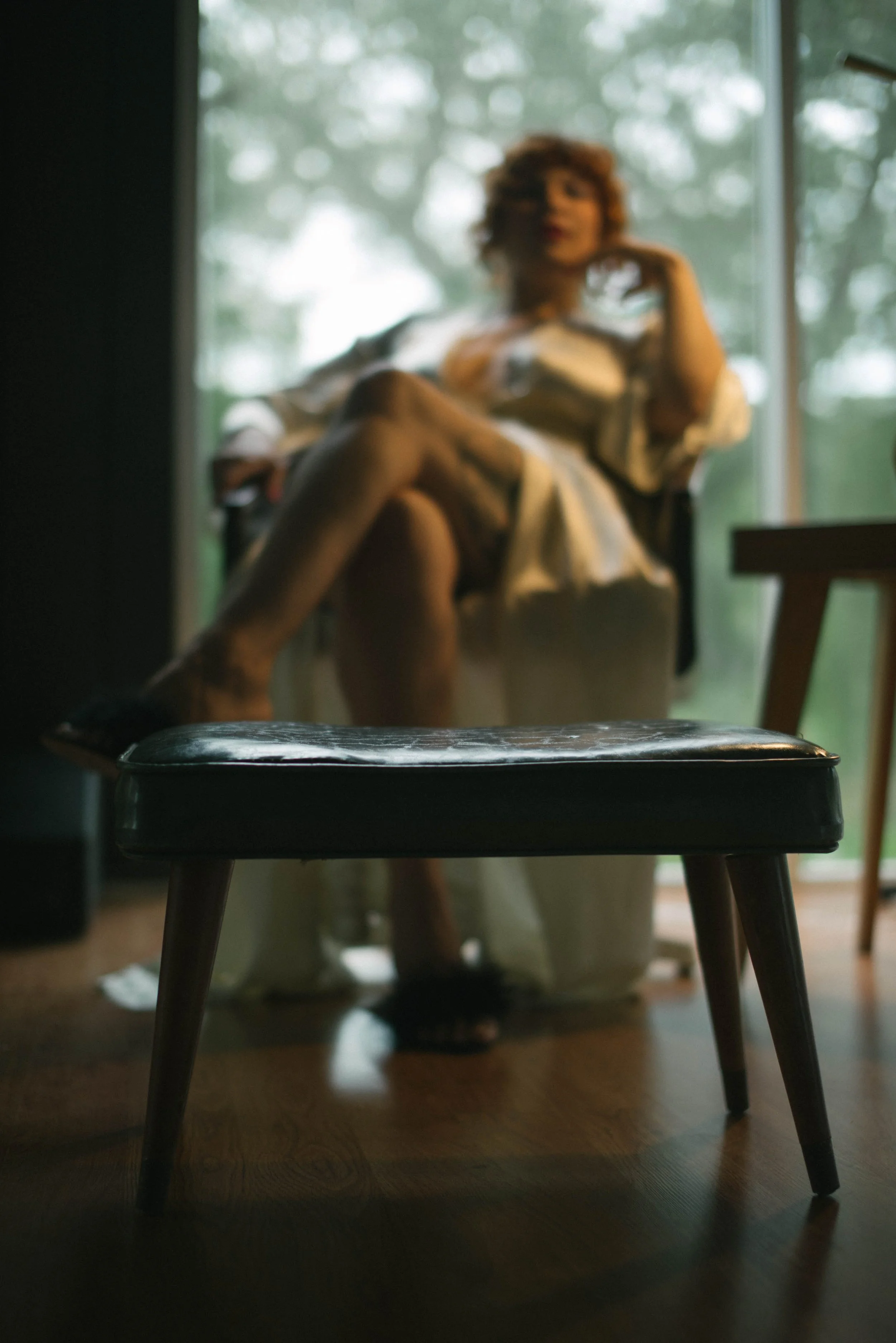 Luxury Dominatrix in NYC Zoey Belladonna sits in a throne looking confident and exuding a sensual femdom energy while looking beneath her at a place for you to kneel.