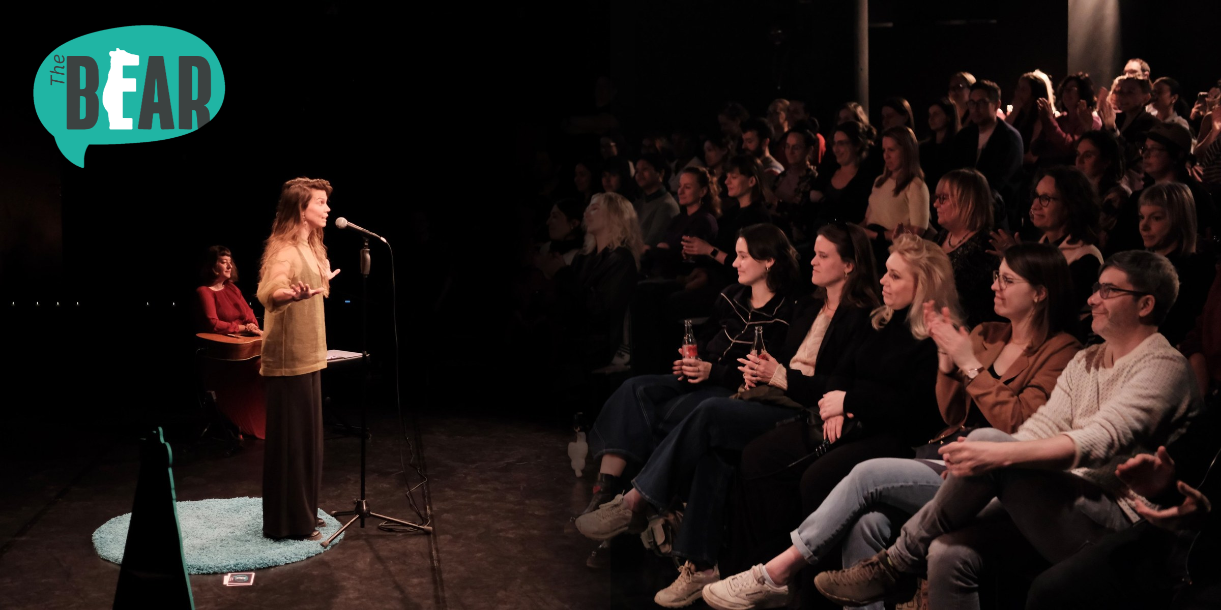 Audience smiling and applauding a storyteller at THE BEAR, Berlin’s English-language live storytelling show.