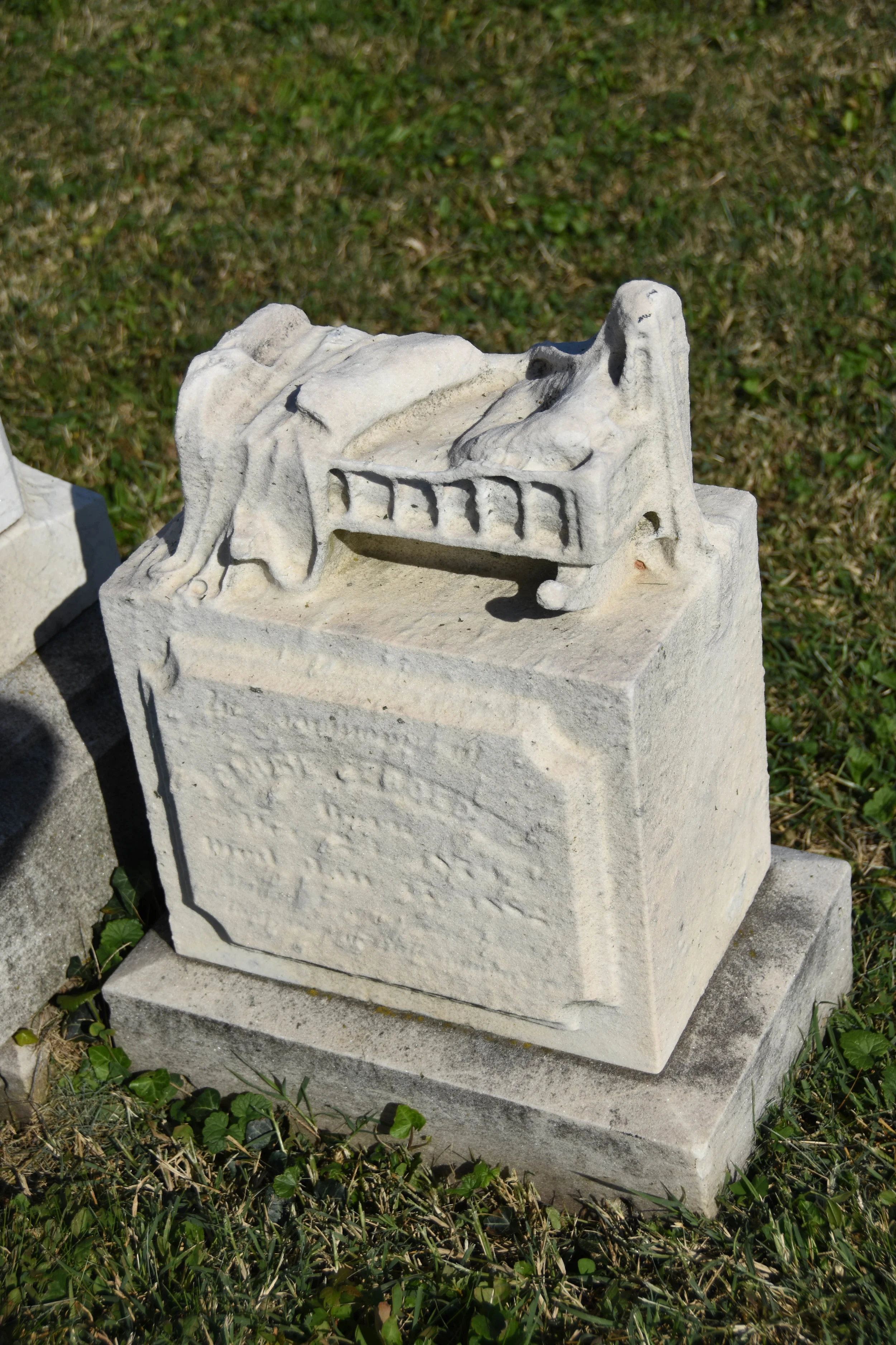 An sculpture of a crib, worn by time, is still visible atop this stone at Baltimore Cemetery.