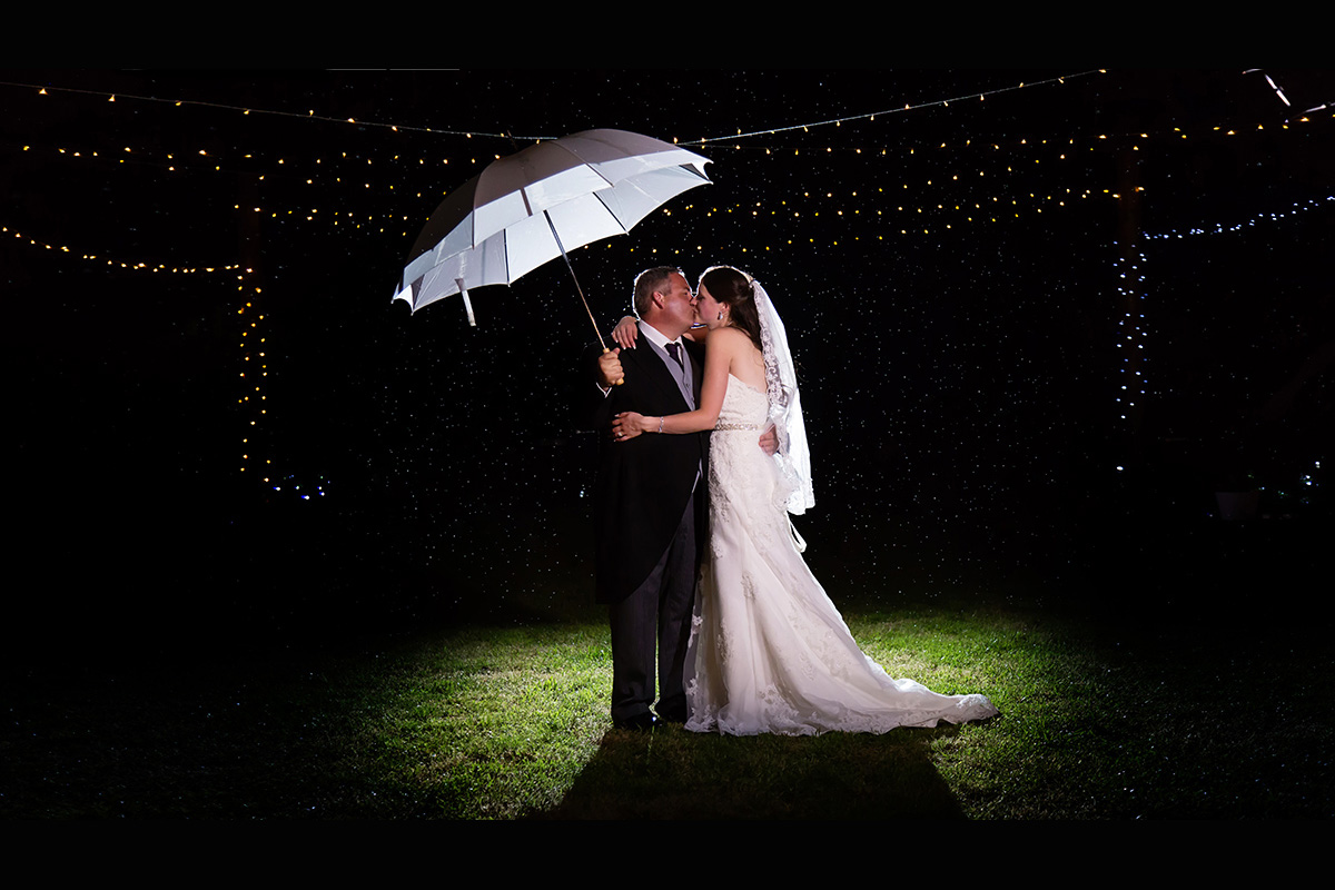 A kiss in the rain for the bride and groom at their Suffolk wedding