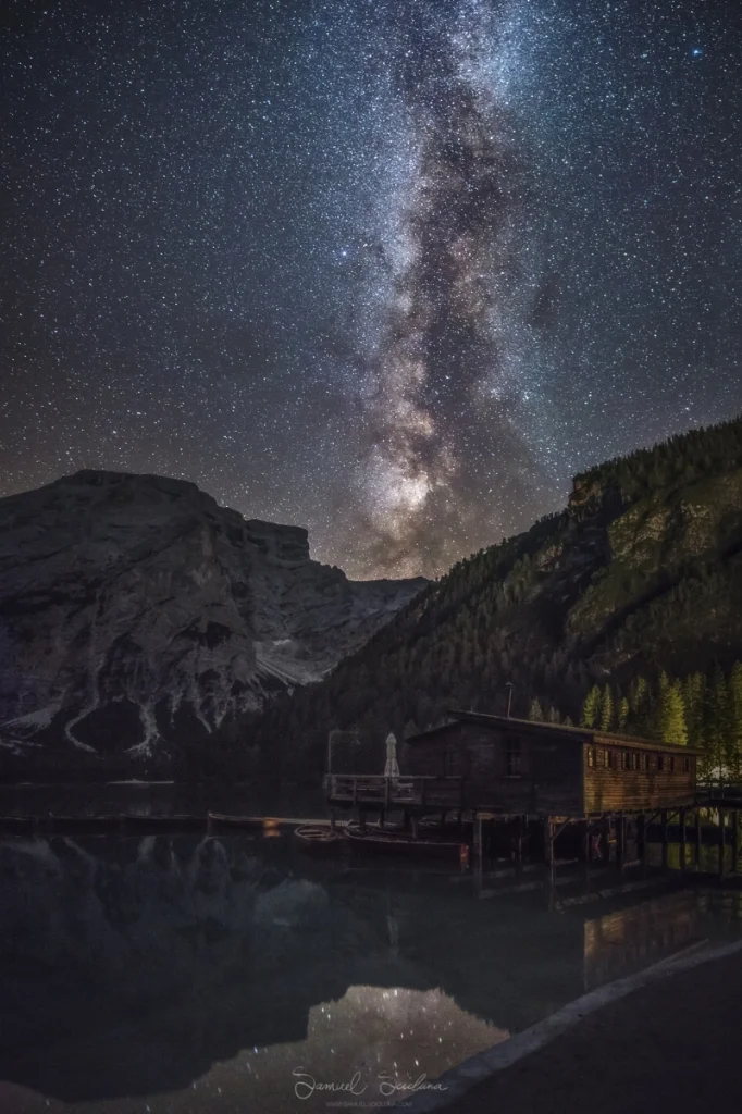 A 4 image vertical panorama showing the Milkyway over the boathouse at Lago di Braies