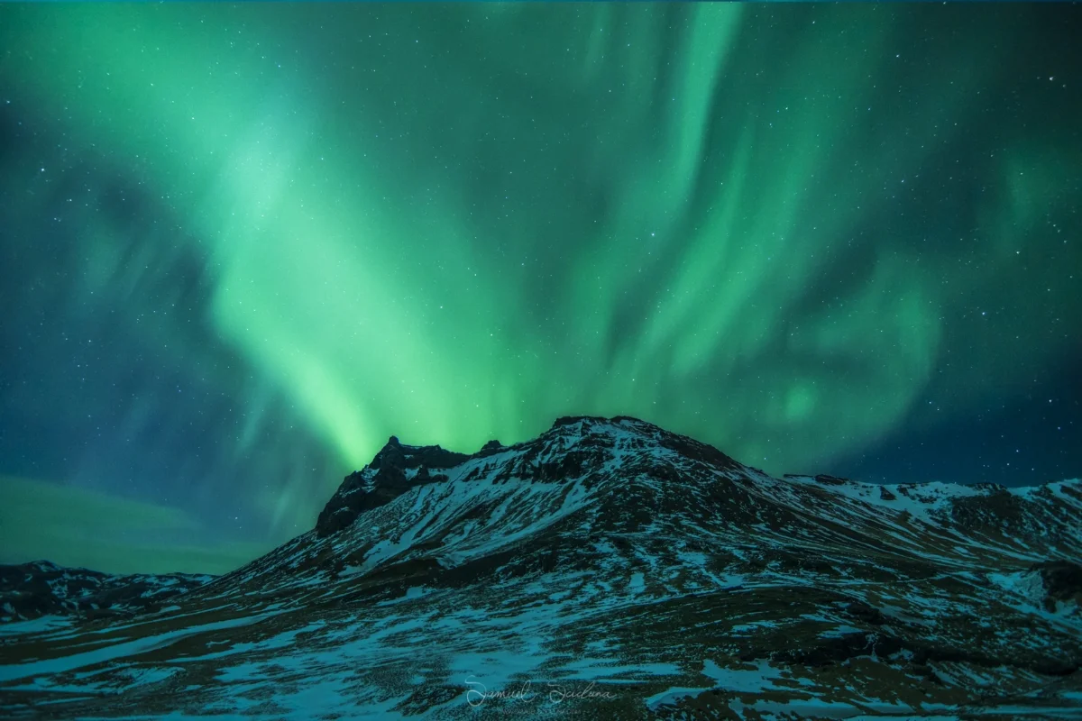 An explosion of Auroral activity behind a random mountain in Iceland.