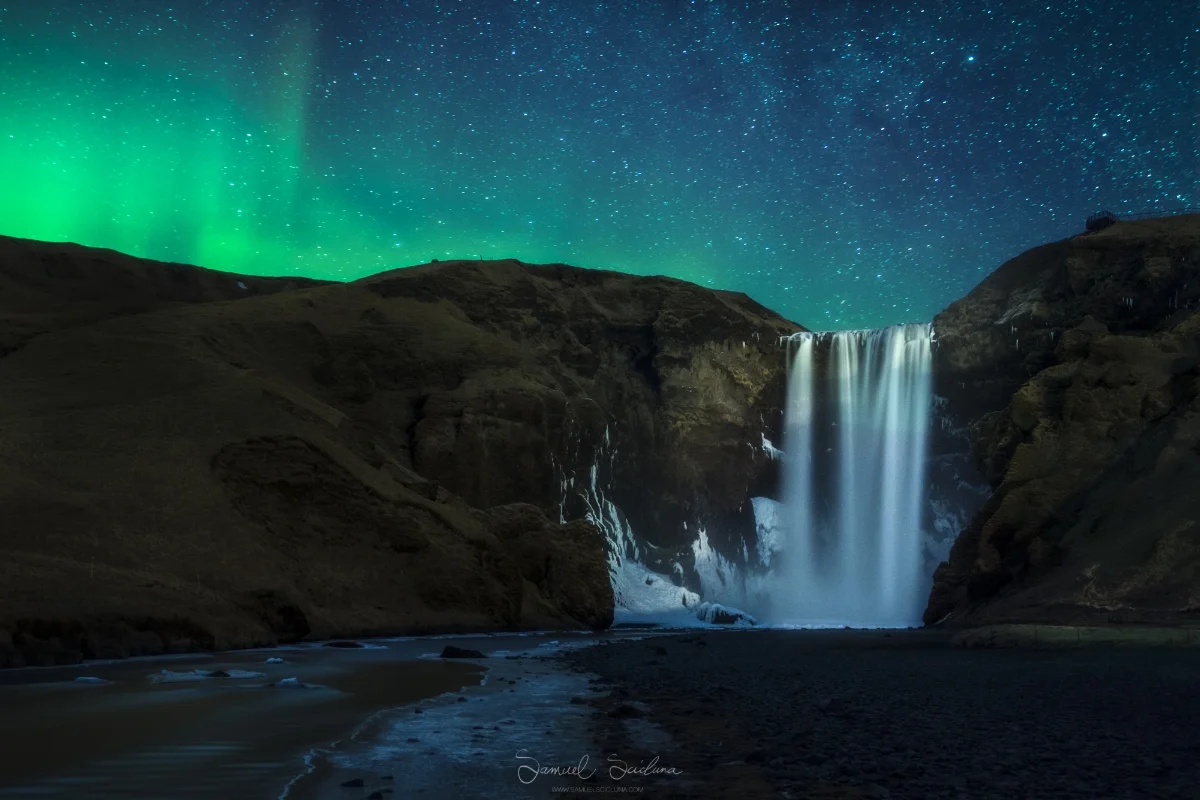 Very faint KP1 - KP2 Auroras glow in the night sky behind Skogafoss waterfall in Iceland.