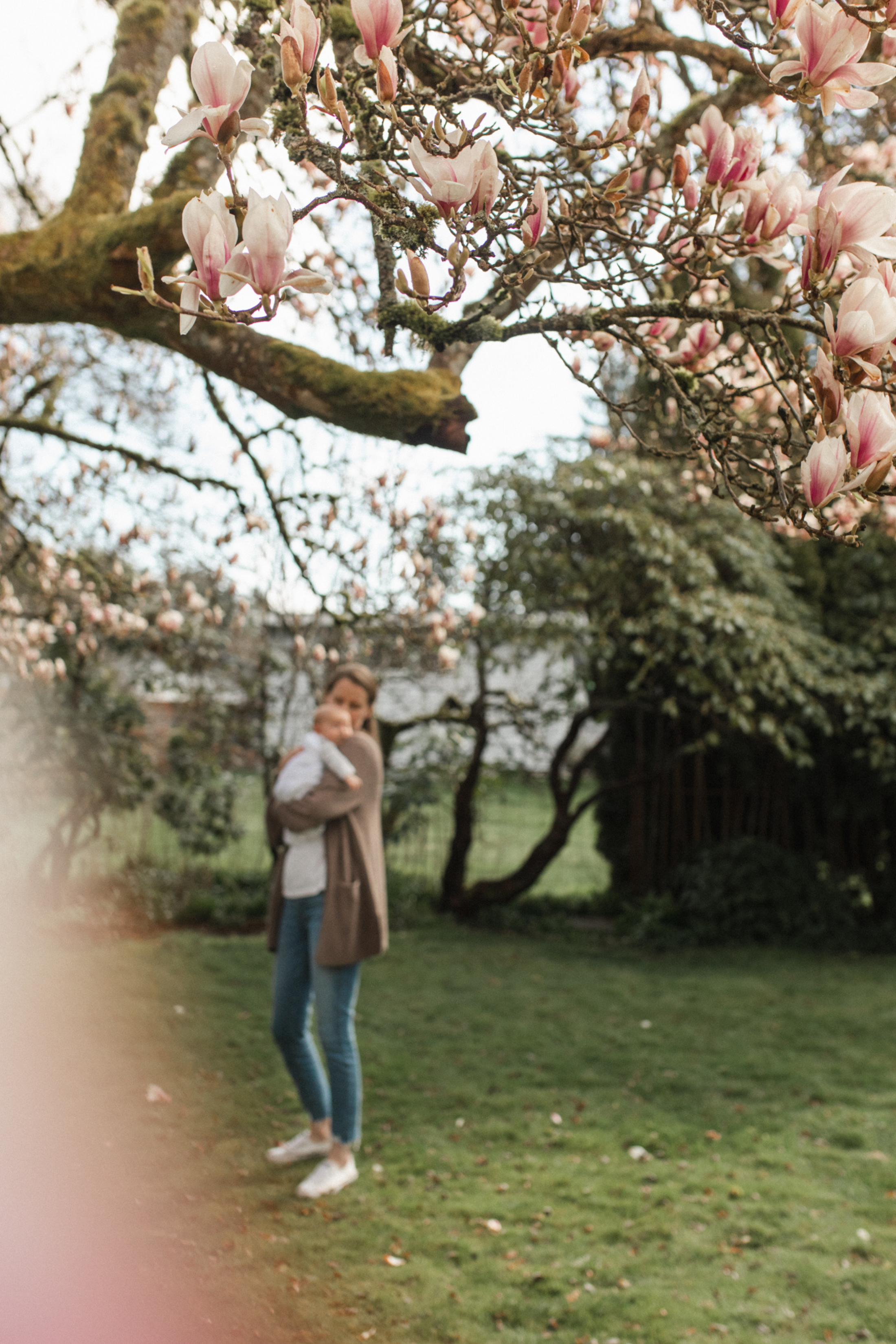 Photograph of  a mother and her newborn outside under a magnolia tree at home in Seattle