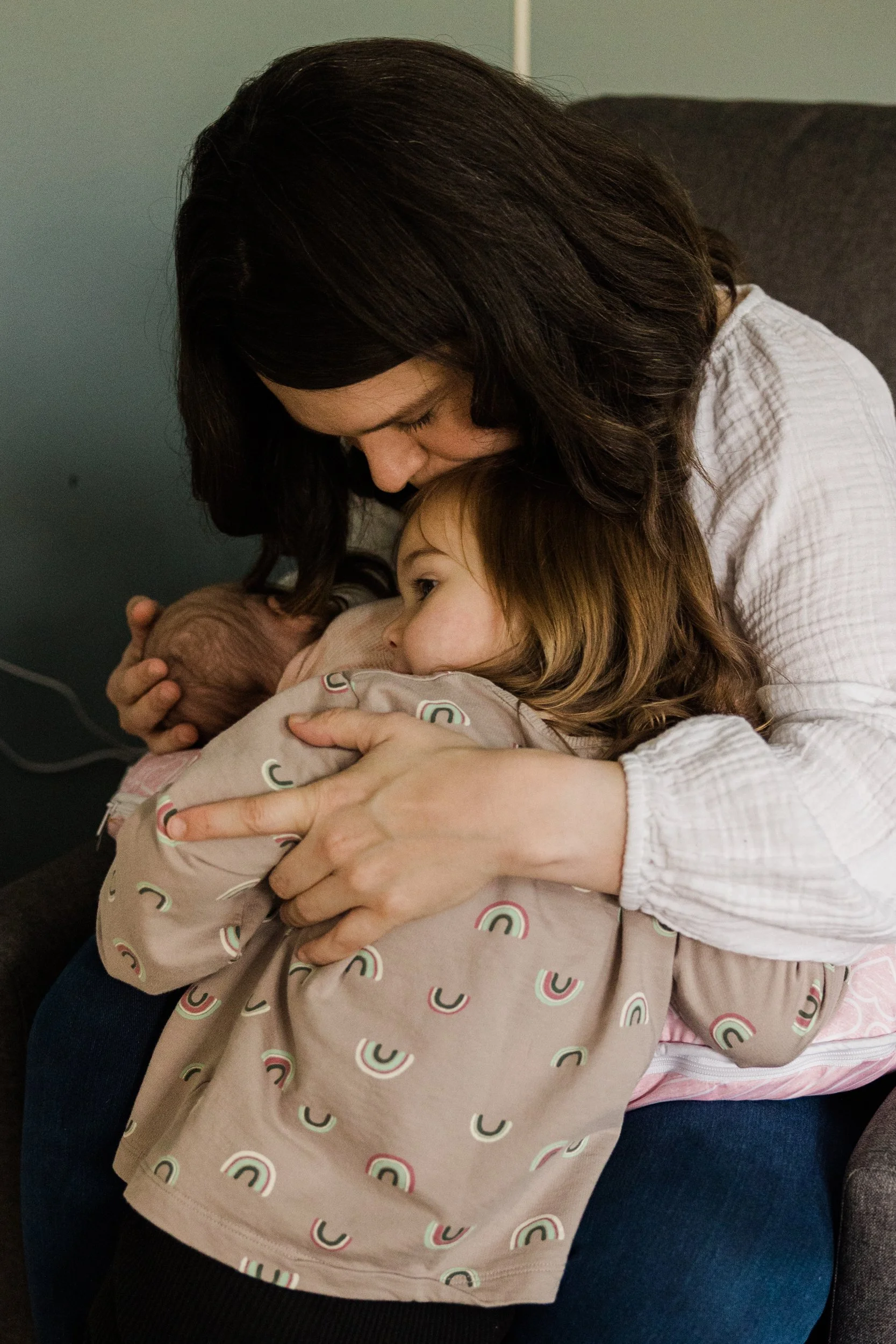 mom cuddles small girl and baby on her lap