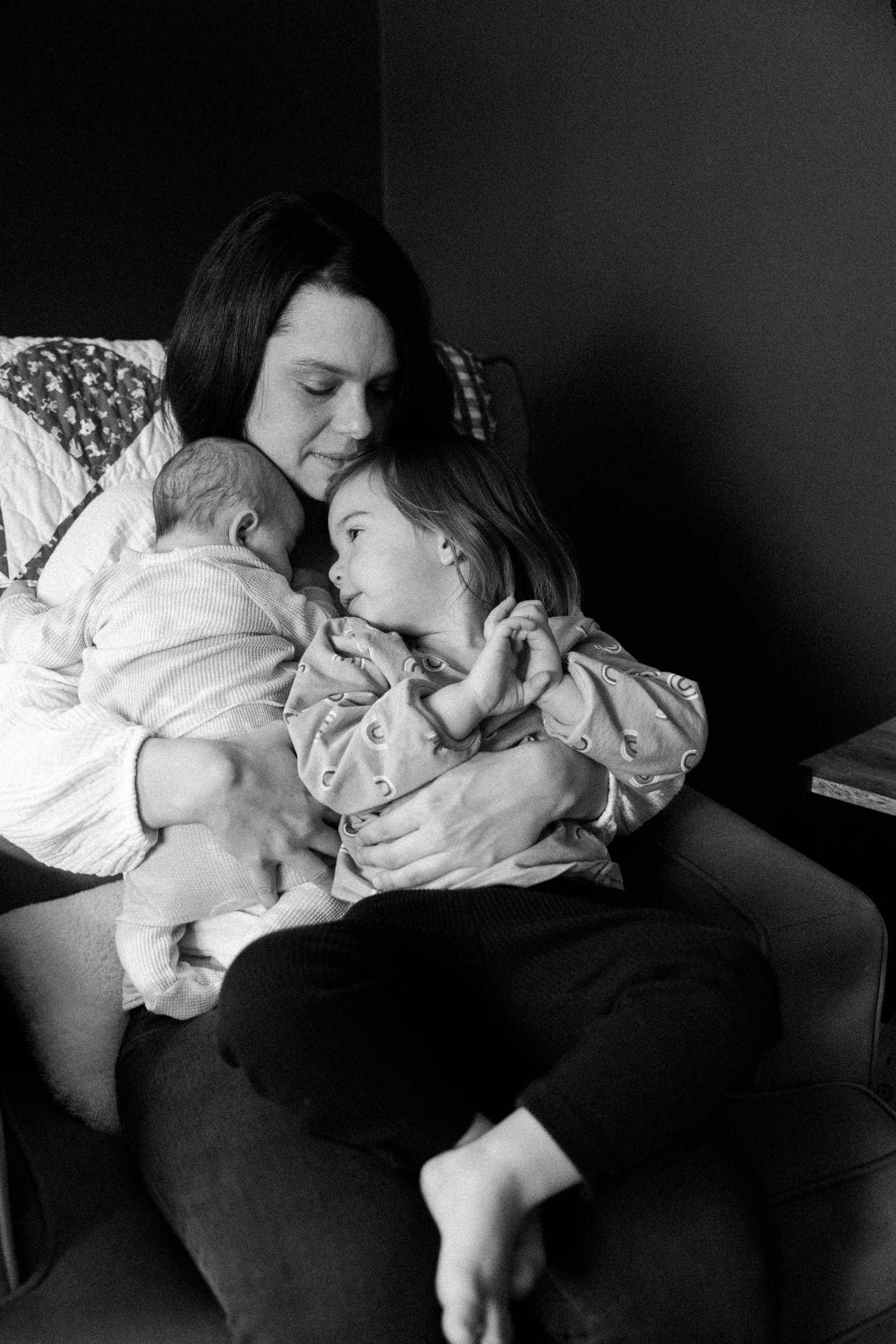 mom sits in rocker while holding baby and small girl
