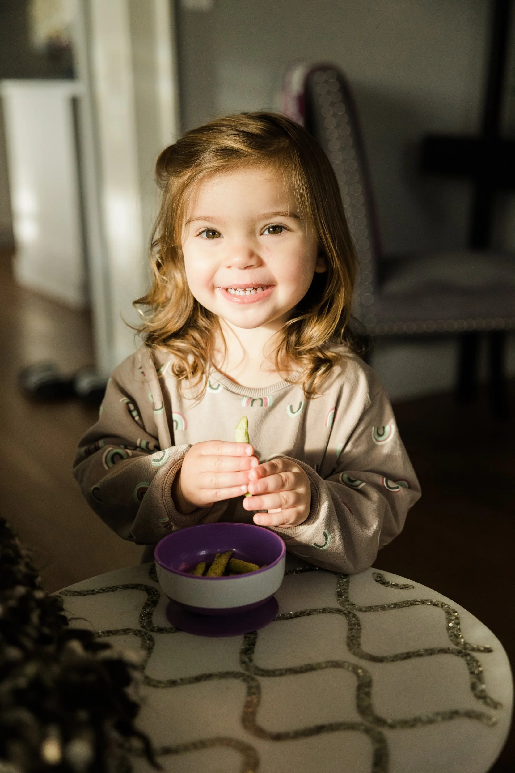 small girl wearing rainbow shirt smiles