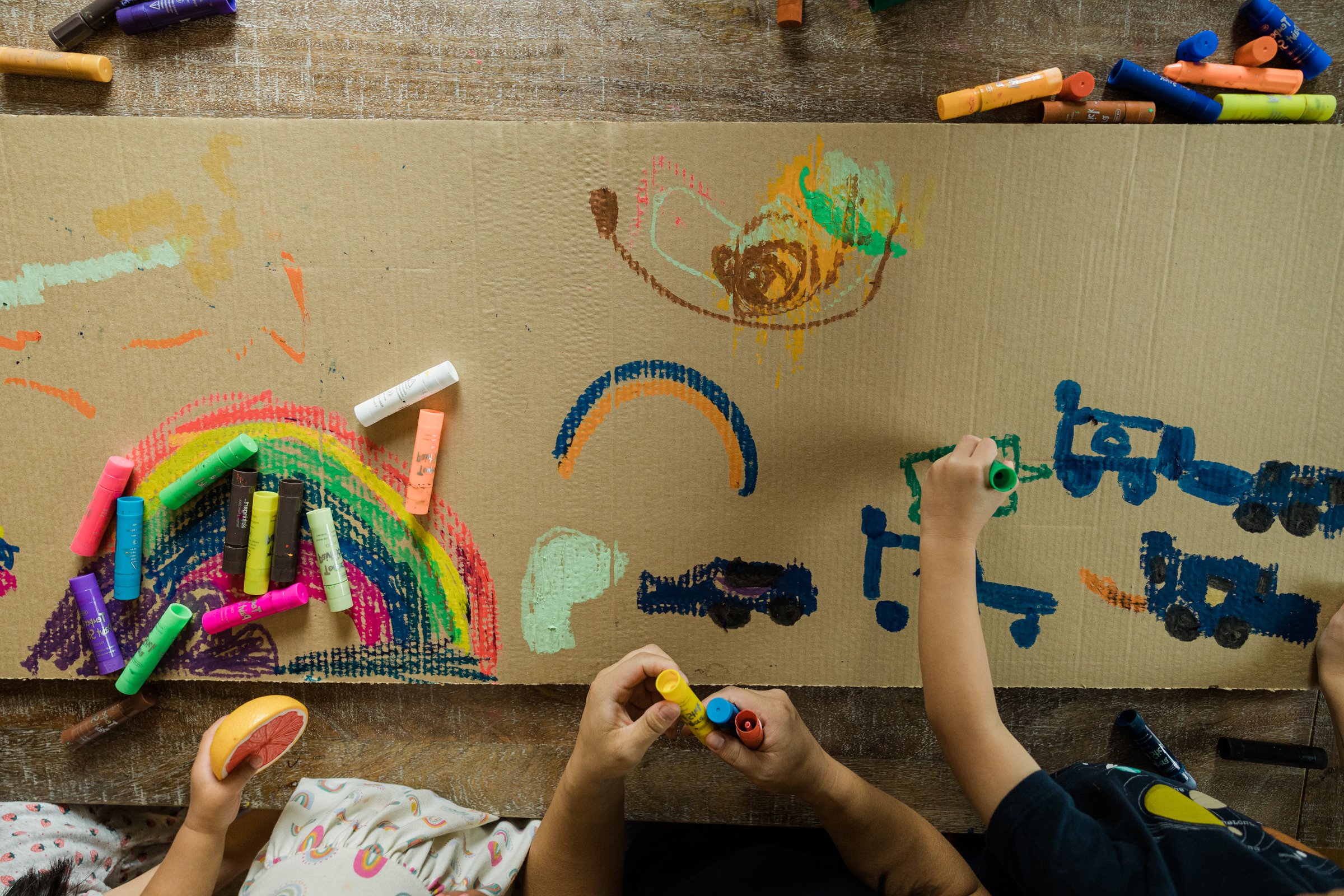 cardboard with colorful children's drawings of rainbows and trucks