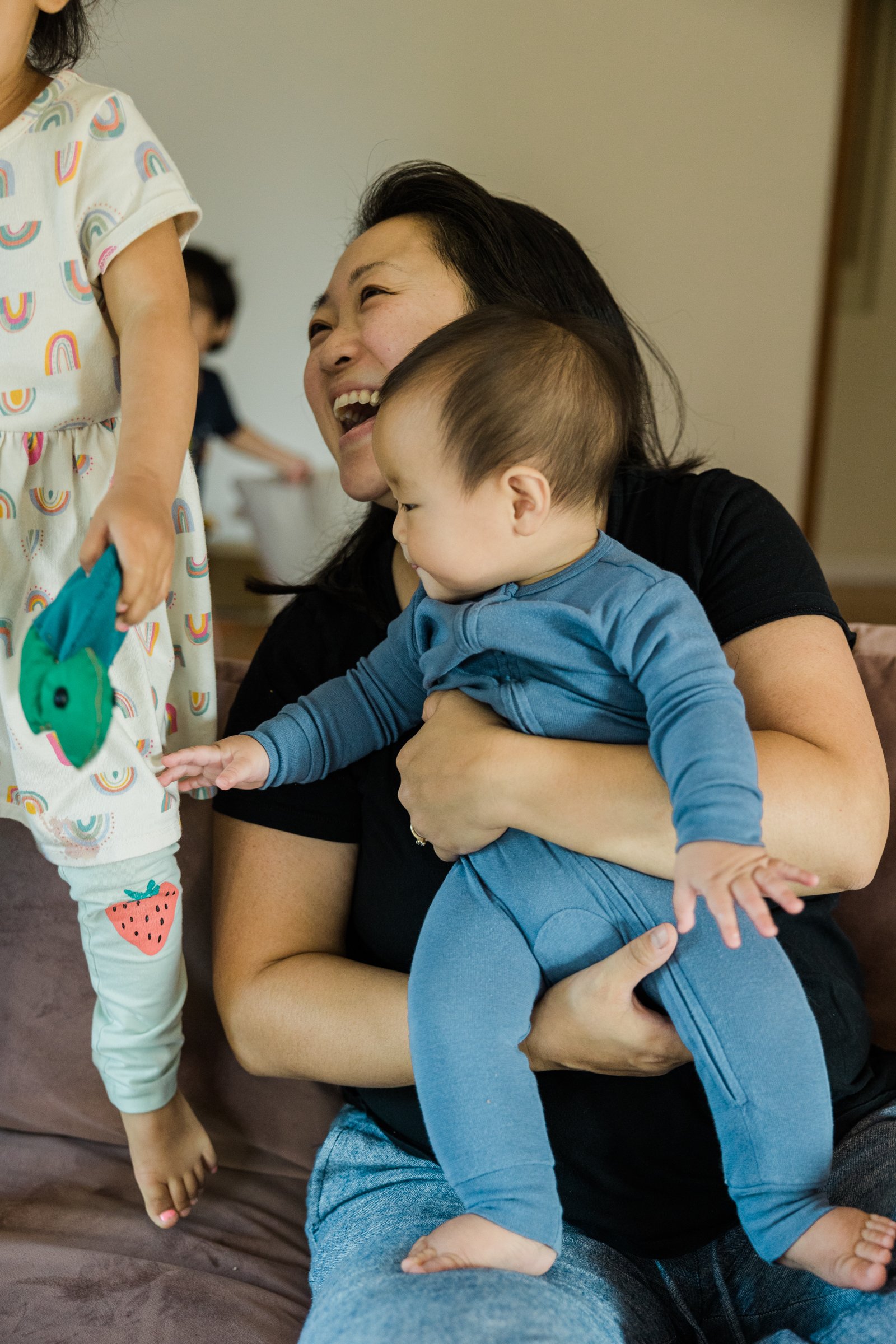 asian mother laughs while holding infant