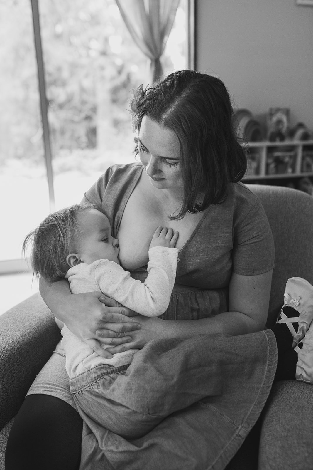 mother sits in rocking chair breastfeeding baby