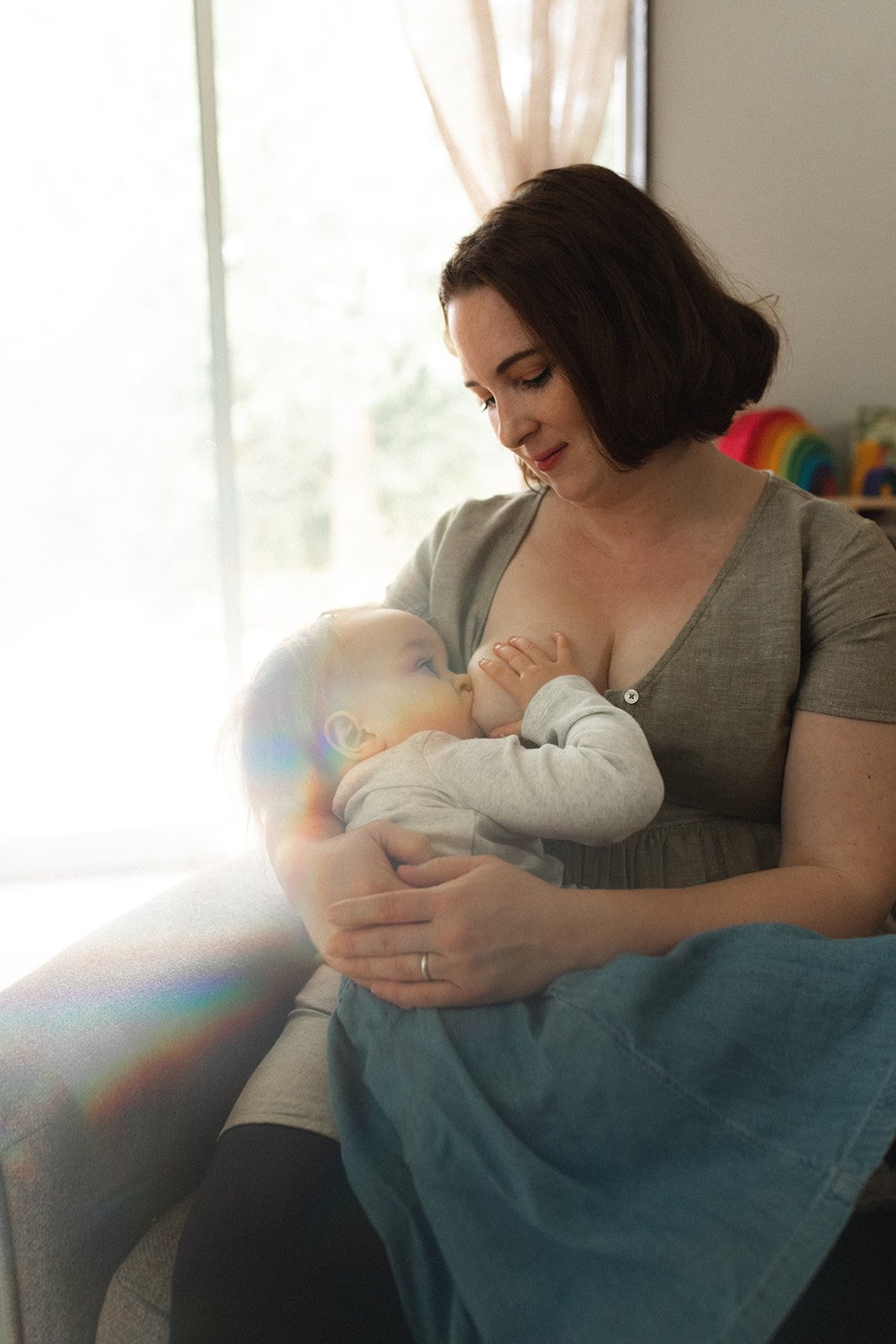 mother sits in rocking chair breastfeeding baby