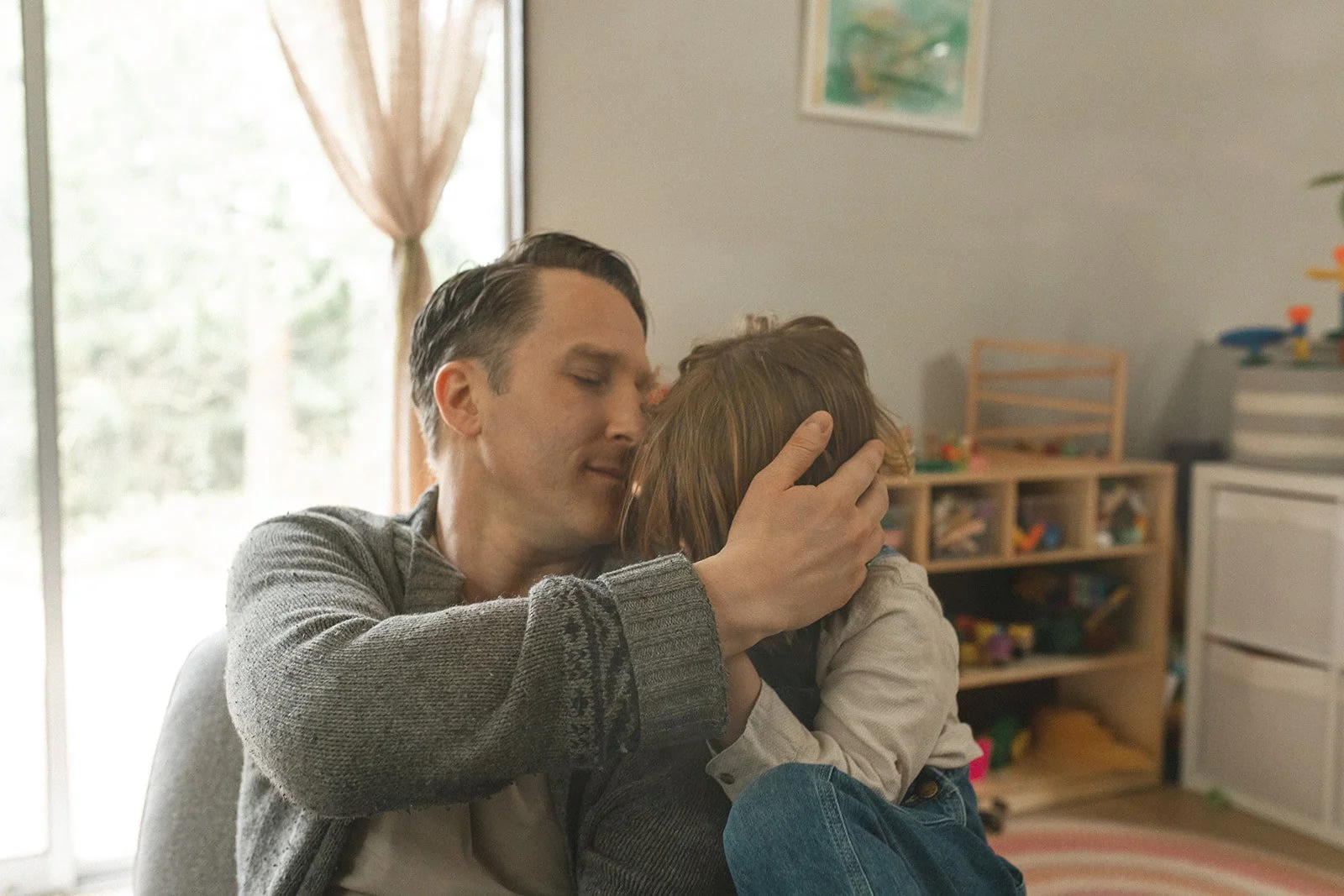 dad holds son on lap and cradles his head with one hand
