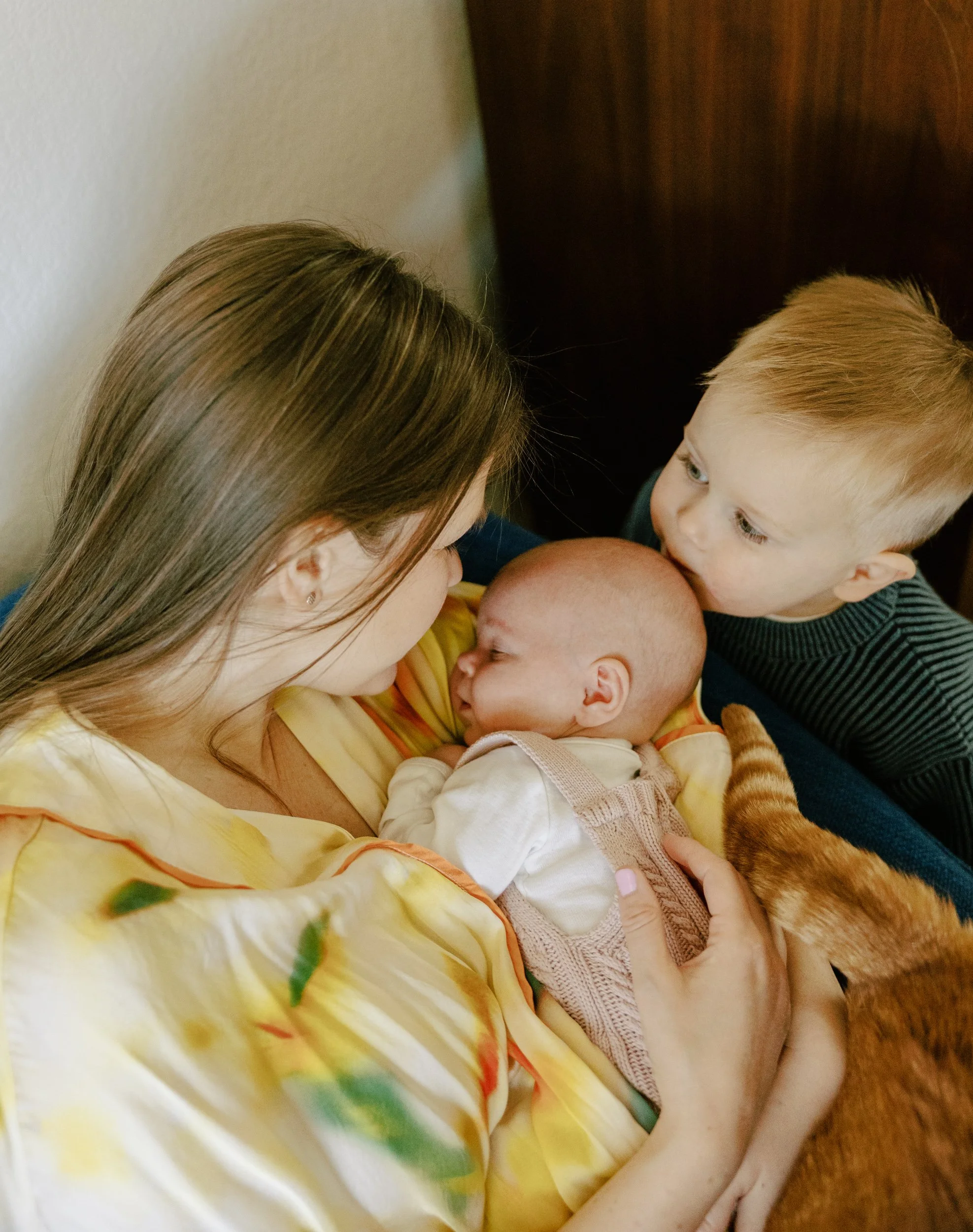 big brother kisses newborn sister on the head at home
